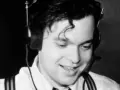 Orson Welles, giovane e sorridente con cuffie, un'immagine che evoca la sua genialità, ma non il suo orson welles causa morte.