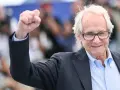 Ken Loach, regista inglese famoso, alza il pugno in segno di vittoria.
