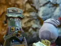 Personaggio a forma di cassettiera verde, con occhi grandi e un sorriso furbo, ricorda un film trash anni 80.