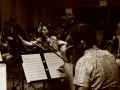 Orchestra di archi registra colonne sonore film italiani. Musicisti concentrati sugli spartiti, con cuffie per il monitoraggio.