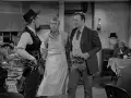 Inquadratura americana di tre uomini in un saloon. Uno indossa un grembiule, gli altri abiti western.