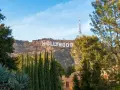 Il cartello "HOLLYWOOD" domina la collina, indicando dove si trova Hollywood, con alberi verdi e un cielo azzurro.