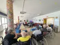 Anziani in un centro diurno partecipano a un'attività, forse un gioco o una lezione. Sembra che sia andata **buona la prima**, con tutti attenti e coinvolti.
