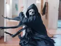 Ghostface, icona del film horror slasher, brandisce un coltello in un corridoio.