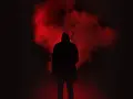 Figura incappucciata nell'oscurità, circondata da fumo rosso. Un'immagine che evoca la differenza tra giallo e noir, tra mistero e oscurità.