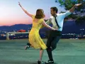 Coppia balla al tramonto, immersa nella musica diegetica che accompagna la loro danza, con la città illuminata sullo sfondo.