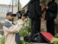 Regista con telecamera in mano, intento a catturare l'essenza di un film d'autore. Sullo sfondo, due uomini discutono.