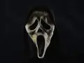 Maschera iconica di Ghostface, simbolo di horror paurosi, con cappuccio nero e sfondo scuro.