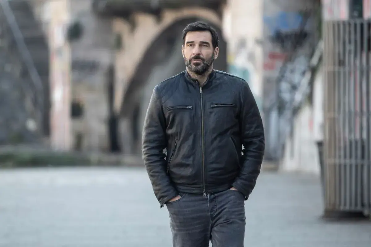 Edoardo Leo, con la sua aria pensierosa, cammina in un vicolo urbano, ricordando forse i suoi ruoli ne I Cesaroni.