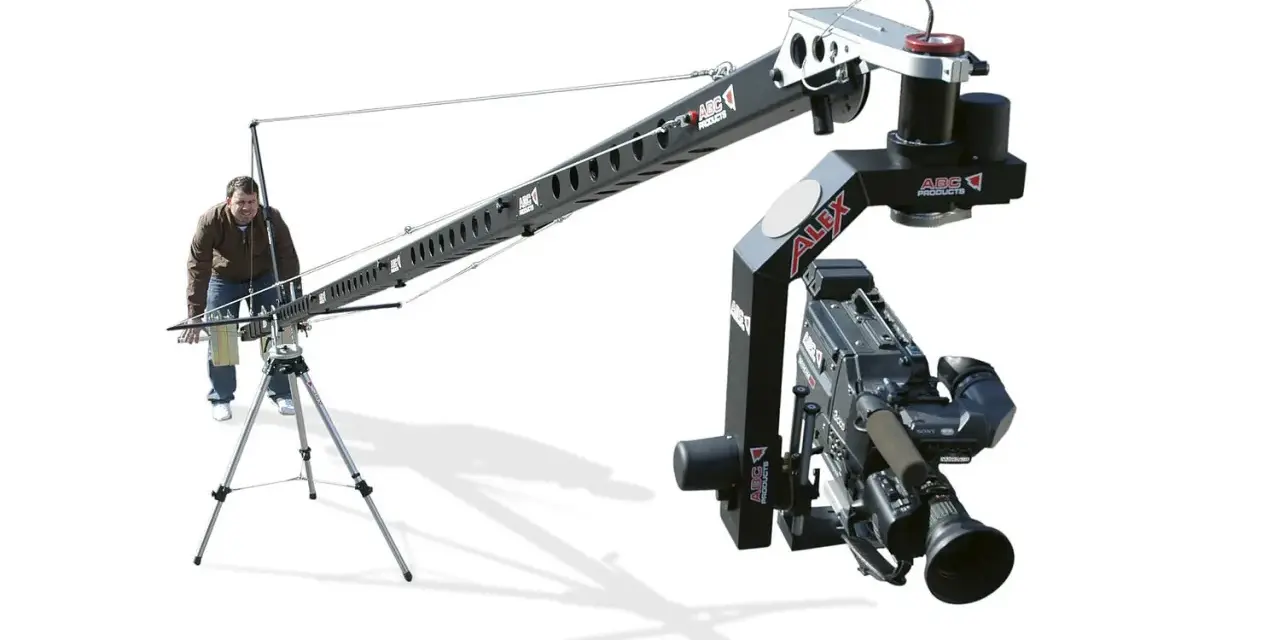 Un uomo manovra un braccio mobile per riprese cinematografiche, un vero crane per il cinema, con una telecamera professionale montata.