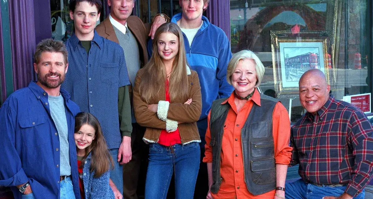 Cast di famiglie serie tv americane anni 2000, sorridono davanti a un negozio.