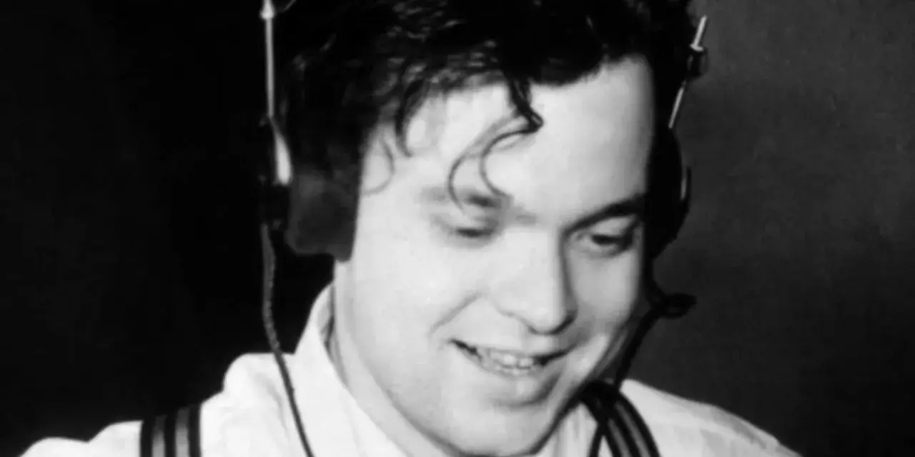 Orson Welles, giovane e sorridente con cuffie, un'immagine che evoca la sua genialità, ma non il suo orson welles causa morte.