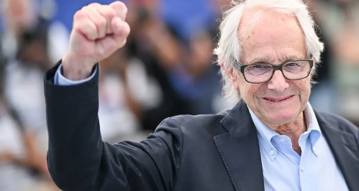 Ken Loach, regista inglese famoso, alza il pugno in segno di vittoria.