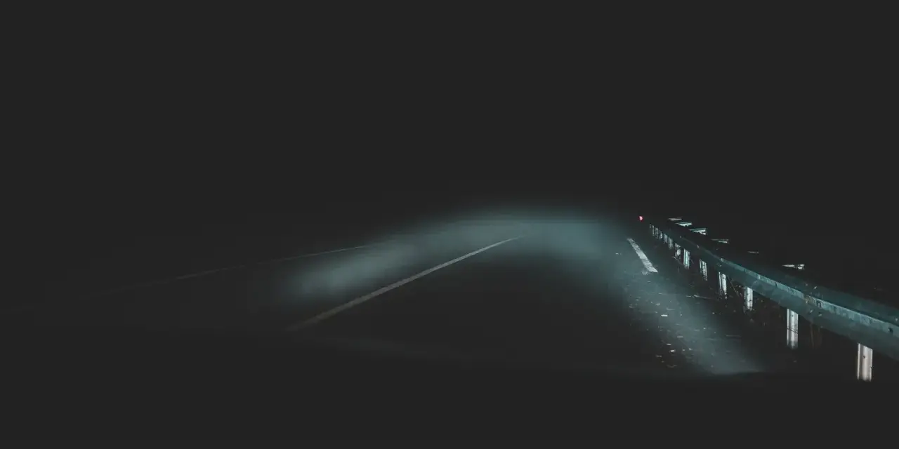 Strada buia e nebbiosa, un'atmosfera che evoca la differenza tra giallo e thriller. I fari illuminano un percorso incerto.