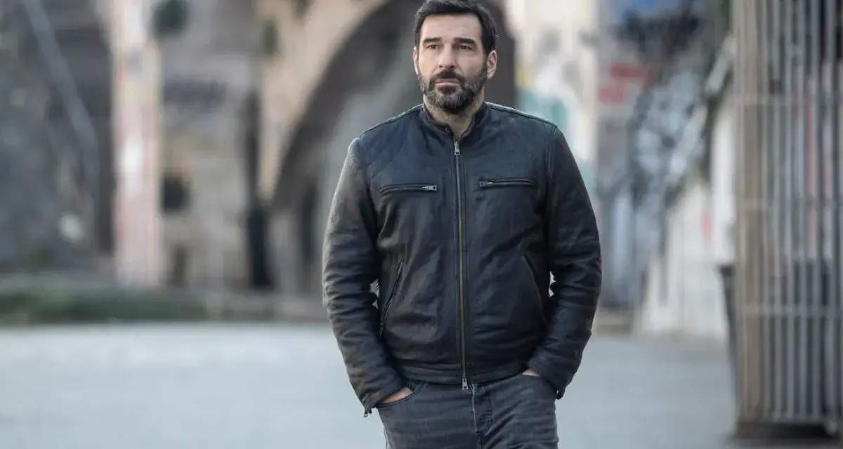 Edoardo Leo, con la sua aria pensierosa, cammina in un vicolo urbano, ricordando forse i suoi ruoli ne I Cesaroni.