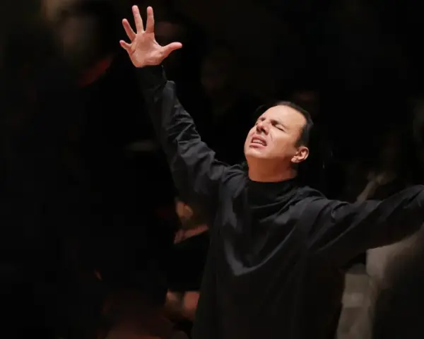 Augusto Biascica, con le braccia alzate e gli occhi chiusi, esprime passione sul palco.