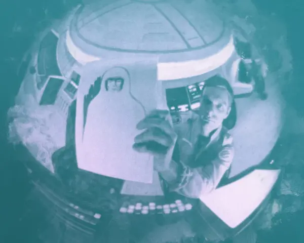 Inquadratura soggettiva: un astronauta in una navicella tiene in mano un disegno di sé stesso con casco.