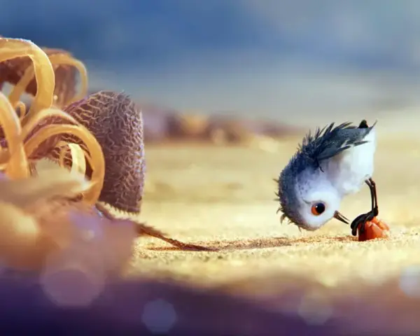 Un pulcino spaventato cerca cibo sulla spiaggia, un'immagine che cattura il significato del cortometraggio "Piper" sulla crescita e il coraggio.