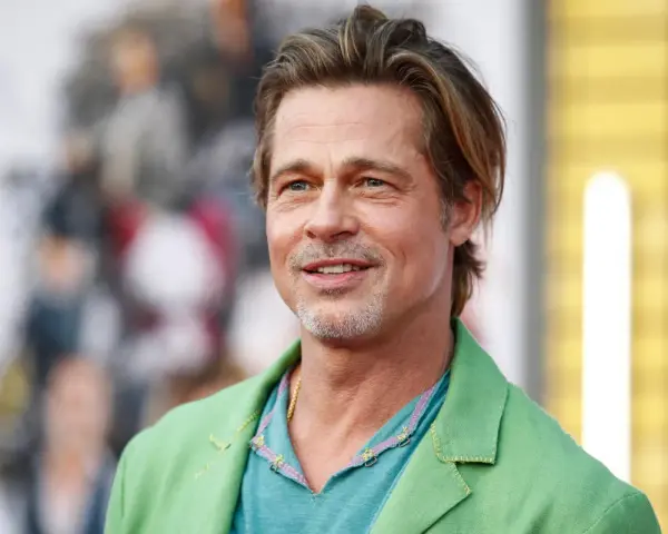Brad Pitt, attore famoso, sorride con un completo verde acceso.