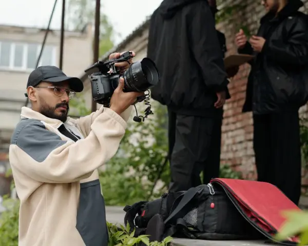 Regista con telecamera in mano, intento a catturare l'essenza di un film d'autore. Sullo sfondo, due uomini discutono.