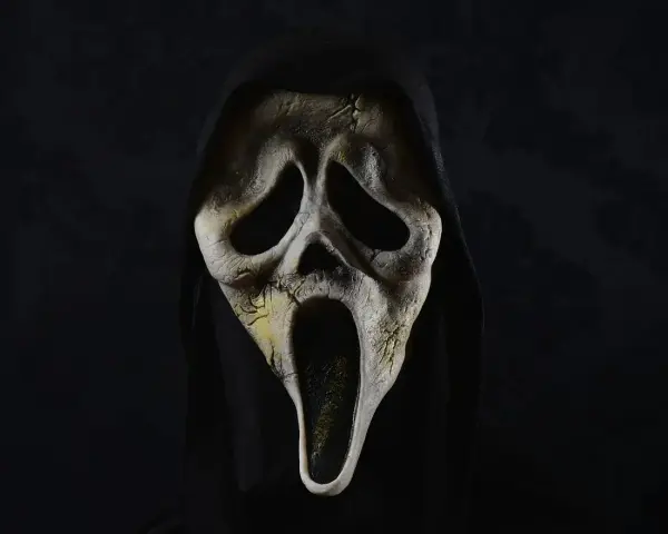 Maschera iconica di Ghostface, simbolo di horror paurosi, con cappuccio nero e sfondo scuro.
