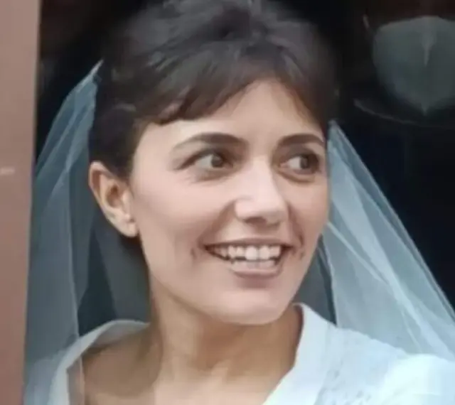 La sposa cast, con un velo leggero, sorride con gioia, pronta per il suo grande giorno.