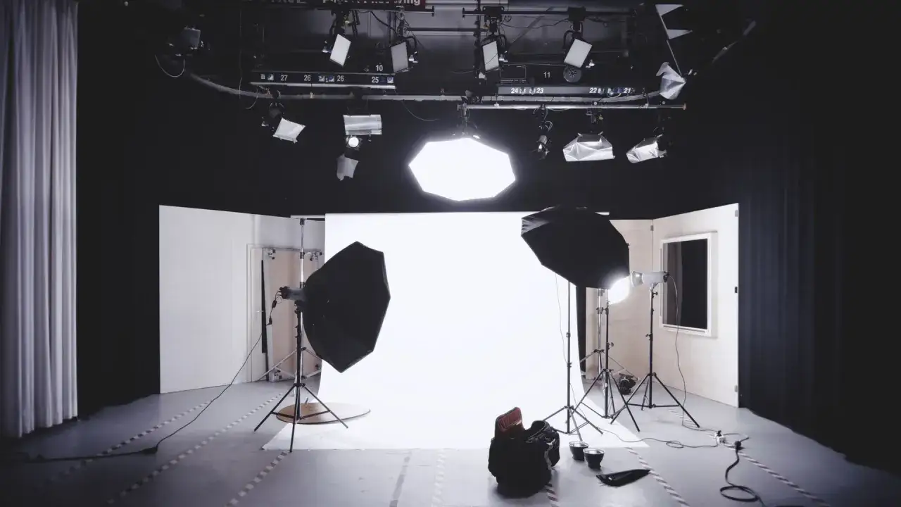 Studio fotografico pronto per le riprese. Luci, fondale bianco e attrezzatura suggeriscono il potenziale per un cortometraggio significato.