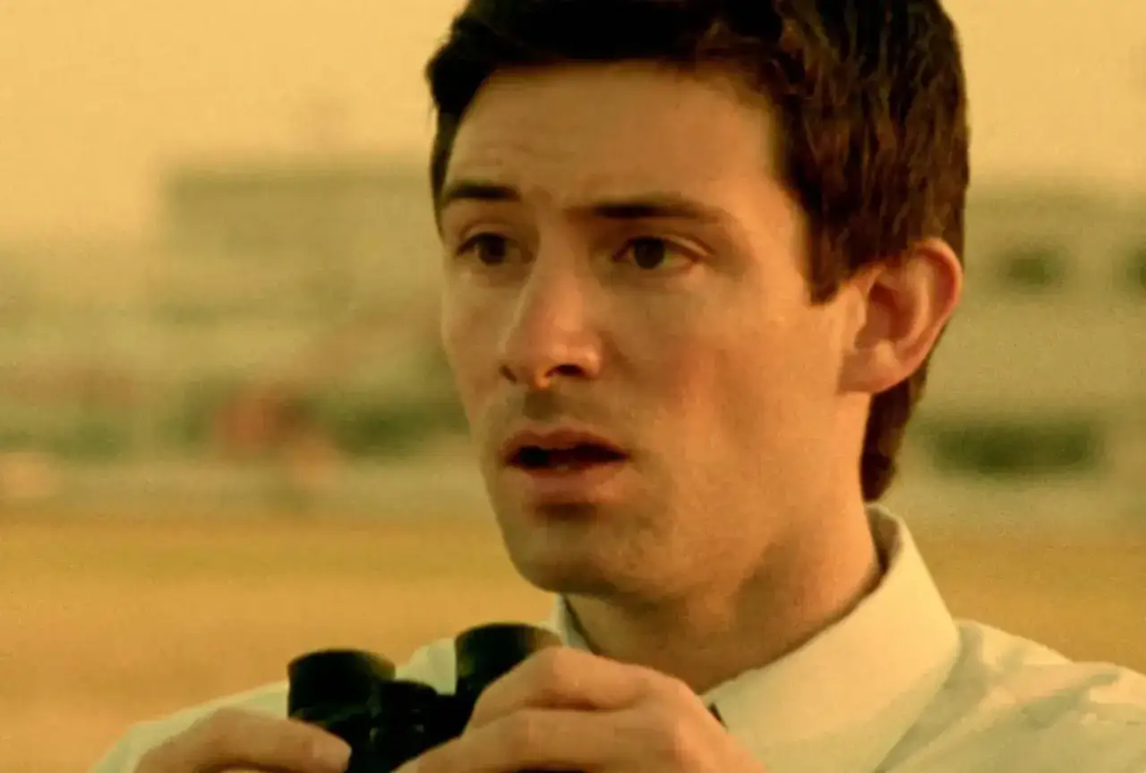 Un uomo con binocolo, in un'atmosfera da film primer, osserva con stupore.