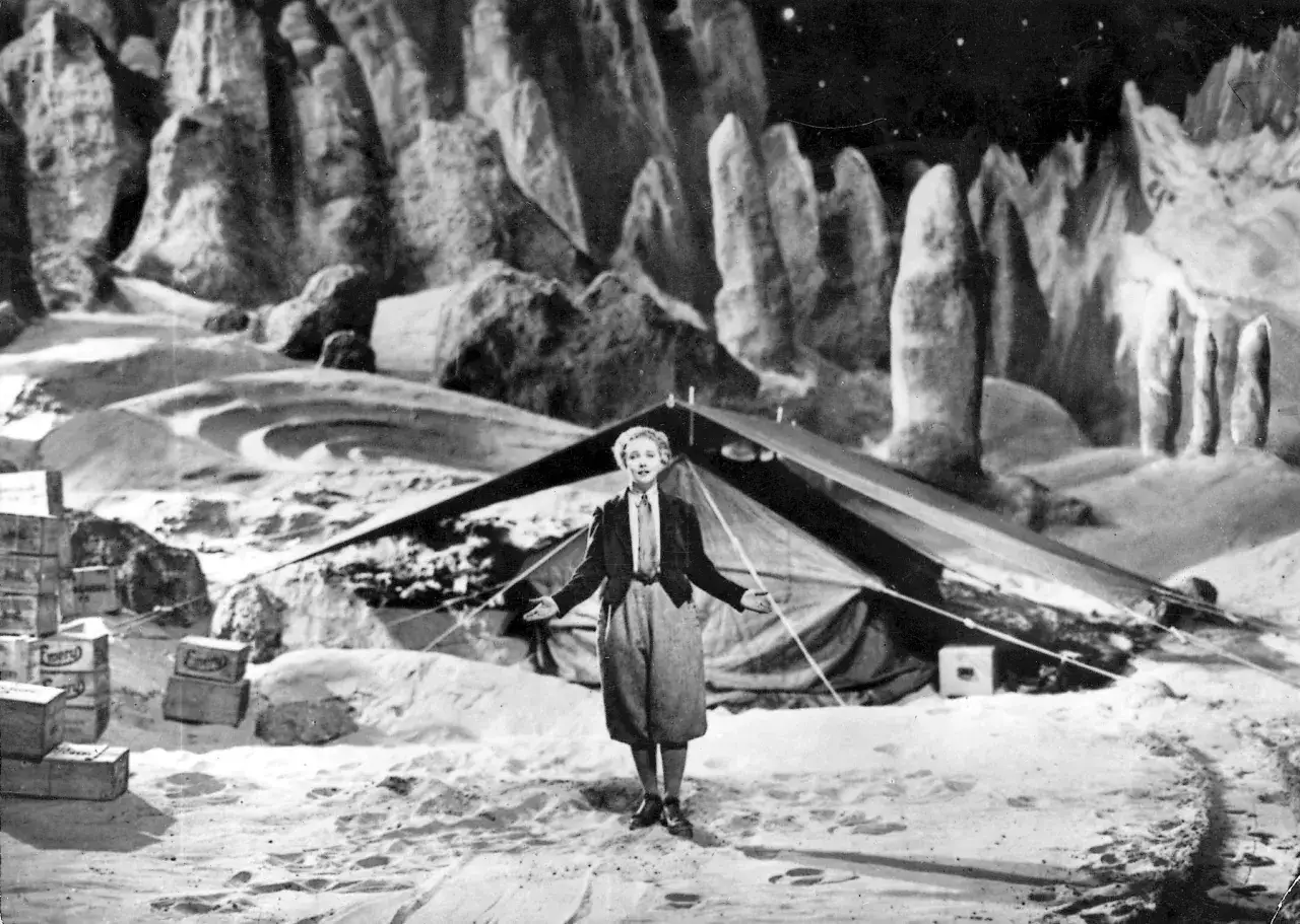 Una donna nella luna, con un paesaggio lunare roccioso e un tendone.