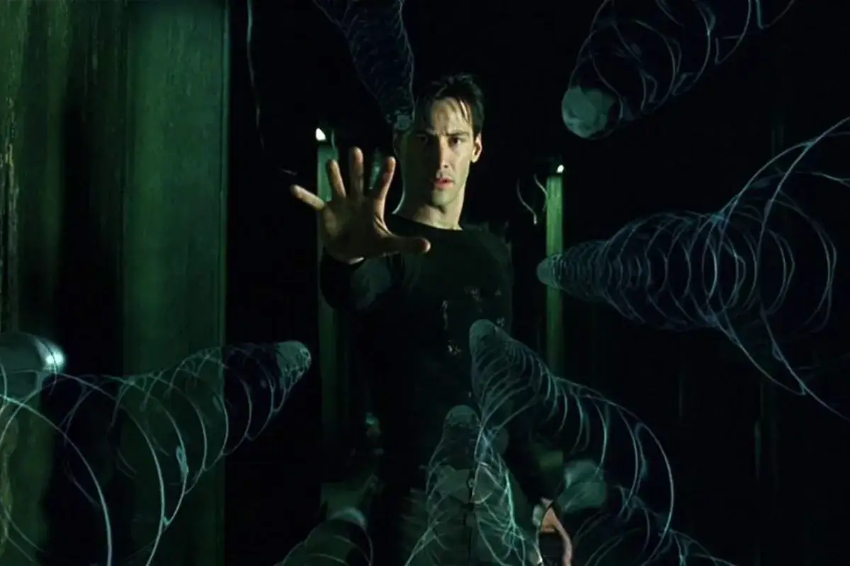 Neo, con la mano tesa, affronta le spirali digitali che rappresentano la trama di Matrix.