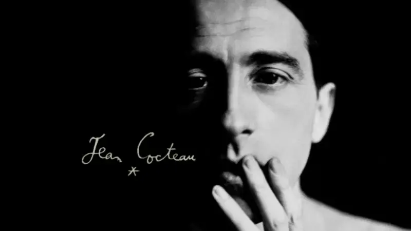 Primo piano di un volto illuminato da un lato, con la firma "Jean Cocteau" in corsivo. Un'immagine evocativa dei suoi film.