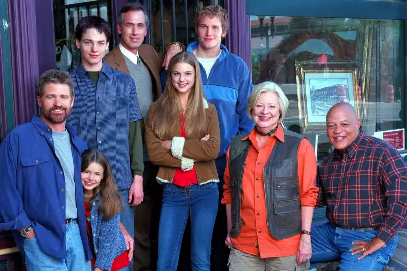 Cast di famiglie serie tv americane anni 2000, sorridono davanti a un negozio.