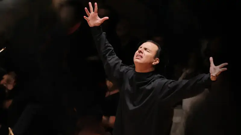 Augusto Biascica, con le braccia alzate e gli occhi chiusi, esprime passione sul palco.