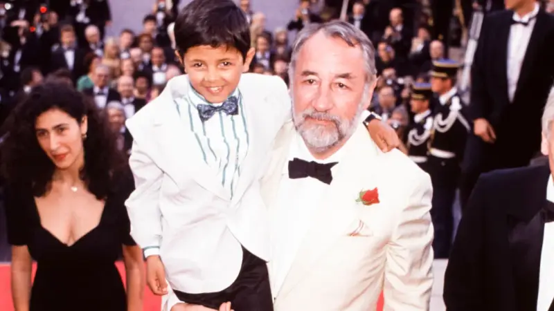 Un bambino sorridente, protagonista di "Nuovo Cinema Paradiso", abbracciato da un uomo con una rosa all'occhiello.